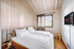 ein weißes Bett in einem Zimmer mit Fenster in der Unterkunft Chalet Dreitorspitz - Riverside in Garmisch-Partenkirchen