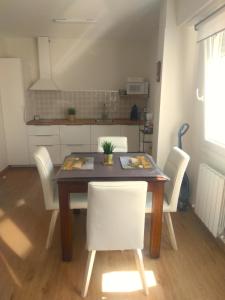 uma mesa de jantar com cadeiras brancas numa cozinha em KIKU Apartments II em Bermeo