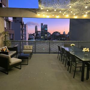 a rooftop patio with tables and chairs and a view of a city at ian Hotel in Buenos Aires