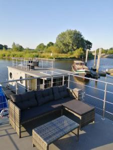 a couch and tables on a boat in the water at Hausboot Lucky in Hattem