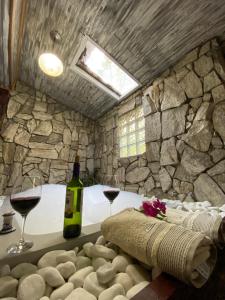 Habitación con 2 copas de vino y pared de piedra. en Pousada Chalés Canto do Rio, en Visconde De Maua