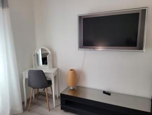 TV de pantalla plana colgada en una pared blanca en 1 Chambre paisible à La Trinité proche de Nice et Monaco, en La Trinité