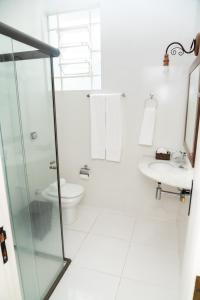 Un baño blanco con inodoro y lavabo. en Pousada Águas de Caxambu, en Caxambu