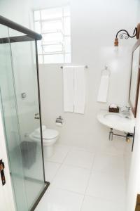 a white bathroom with a toilet and a sink at Pousada Águas de Caxambu in Caxambu