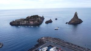 an island in the ocean with boats in the water at L'Isola e i Faraglioni house in Acitrezza