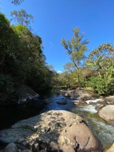 a river with rocks and trees on the side at Pousada Chalés Canto do Rio in Visconde De Maua