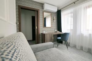 ein Schlafzimmer mit einem Sofa, einem Schreibtisch und einem Spiegel in der Unterkunft Hotel Zlatá Hvězda in Litomyšl