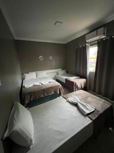 Habitación con 2 camas en una habitación con ventana en Pousada Praia Bela, en Maragogi