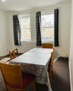 エディンバラにあるSIMPLE 2BED FLAT IN EDINBURGH.のダイニングルーム(テーブル、椅子、窓2つ付)