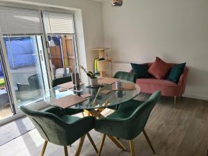 a living room with a glass table and green chairs at Ria's B n B in Pocklington