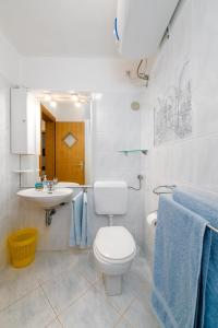 a white bathroom with a toilet and a sink at Apartments Melita in Crikvenica