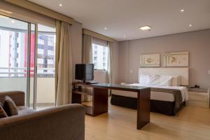 a hotel room with a bed and a desk with a tv at 360 Saint Charbel - Apartamentos mobiliados in Sao Paulo