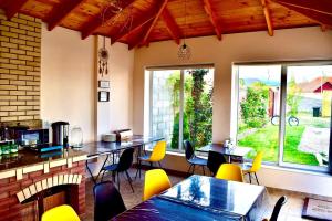 uma sala de jantar com mesas, cadeiras e janelas em Guest House “Aura” em Cholpon-Ata