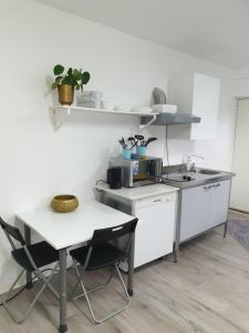 a white kitchen with a table and a table and a counter at Comfortable apartment, 10min Airport in Stavanger