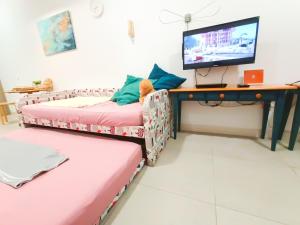 a room with two beds and a desk with a television at Afiniti, 2 min walk to legoland and Gleneagles Hospital By Hint Homestay in Nusajaya