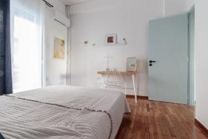 a white bedroom with a bed and a desk at Hamaretou Apartment in Sparti
