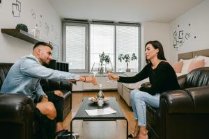 Ein Mann und eine Frau sitzen auf Sofas im Wohnzimmer in der Unterkunft Flora Cozy Apartment in Bratislava