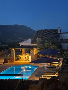 une piscine avec deux parasols et un bâtiment dans l'établissement Casas Demi verhuurhuis, à Vélez-Blanco