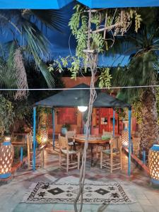 a table with chairs and an umbrella on a patio at Riad Dades Birds in Boumalne
