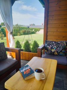 a coffee table with a book and a cup of coffee at Całoroczny dom w sercu Mazur in Węgorzewo