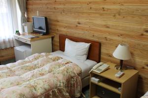 a bedroom with a bed and a desk with a television at Sansuikan Kawayu Midoriya in Hongu