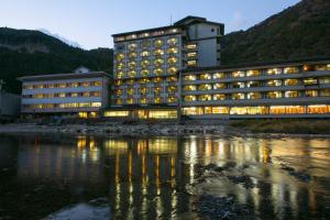 a building with its lights on next to a body of water at Sansuikan Kawayu Midoriya in Hongu