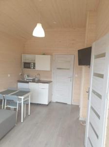 a room with a kitchen with a table and a door at Domki Przy Pogodnej in Ustronie Morskie