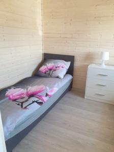a room with a bed with pink flowers on it at Domki Przy Pogodnej in Ustronie Morskie