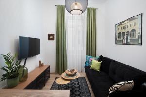 a living room with a black couch and a flat screen tv at Apartment Deluxe Ana in Pula