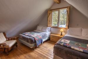 1 dormitorio con 2 camas, silla y ventana en Timbers Resort en Fairmont Hot Springs