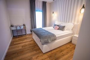 a large white bed in a room with wood floors at Villa 7 in Međugorje +30 photos
