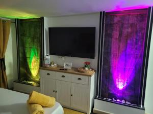 een slaapkamer met 2 ramen met paars en groen licht bij Chabela's water wall in Lajita