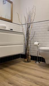 La salle de bains est pourvue de toilettes et d'un vase avec des branches. dans l'établissement Appartamento Careggi con posto auto, à Florence