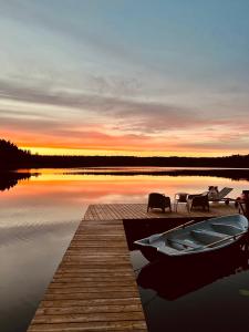ein Dock mit einem Boot auf dem Wasser bei Sonnenuntergang in der Unterkunft Viesuliškės Lakeside Glamping in Lakaja