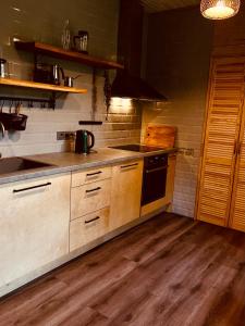 a kitchen with wooden cabinets and a stove top oven at Viesuliškės Lakeside Glamping in Lakaja