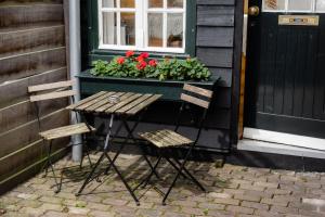 two chairs and a table in front of a house with a window at The Cabin at Zwolle Centraal in Zwolle