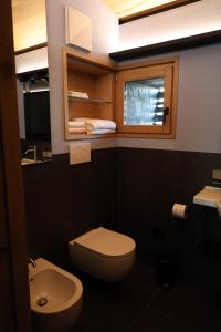 a bathroom with a toilet and a sink and a window at Roggia dei Cedri in Valdobbiadene