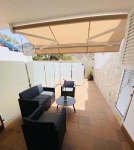 un patio con 2 sofás y una mesa bajo una sombrilla en VV Ancla, en Puerto de Mogán