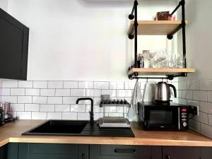 encimera de cocina con fregadero y microondas en Hotel Apartment Two Bedroom Ferrum Wembley Park en Londres