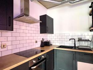 a kitchen with black cabinets and pink tiles on the wall at Hotel Apartment Two Bedroom Ferrum Wembley Park in London