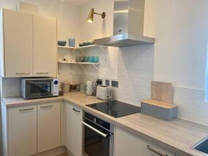 a kitchen with white cabinets and a sink and a microwave at Beach home with garden, close to New Forest in Bournemouth