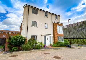 a large white building on a city street at Spacious House - Close to City Centre - Free Parking, Fast Wifi, Smart TVs with Netflix by Yoko Property in Milton Keynes