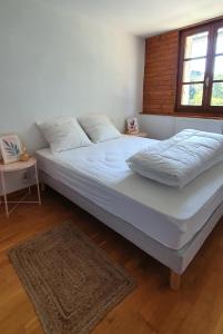 uma grande cama branca num quarto com uma janela em Gite Puy De Dôme em Aydat