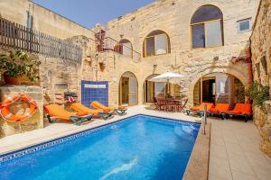 a swimming pool with orange chairs next to a building at Lellux Holiday Home in Nadur