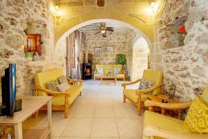 a living room with yellow furniture and a stone wall at Lellux Holiday Home in Nadur