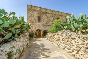 a stone wall next to a building with a cactus at Lellux Holiday Home in Nadur