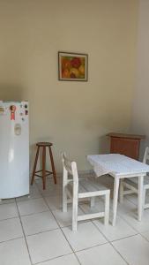 uma cozinha com uma mesa e um frigorífico branco em CHALÉ do LÚ ILHABELA em Ilhabela