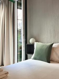 łóżko z zieloną poduszką obok okna w obiekcie Serendipity Apartments - Montenapoleone w Mediolanie