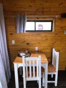 uma mesa de madeira e cadeiras num quarto com uma janela em Bahía em Punta Del Diablo