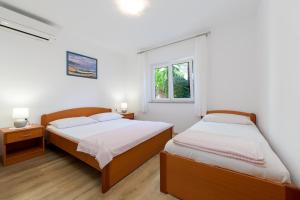 a bedroom with two beds and a window at Apartments Melita in Crikvenica